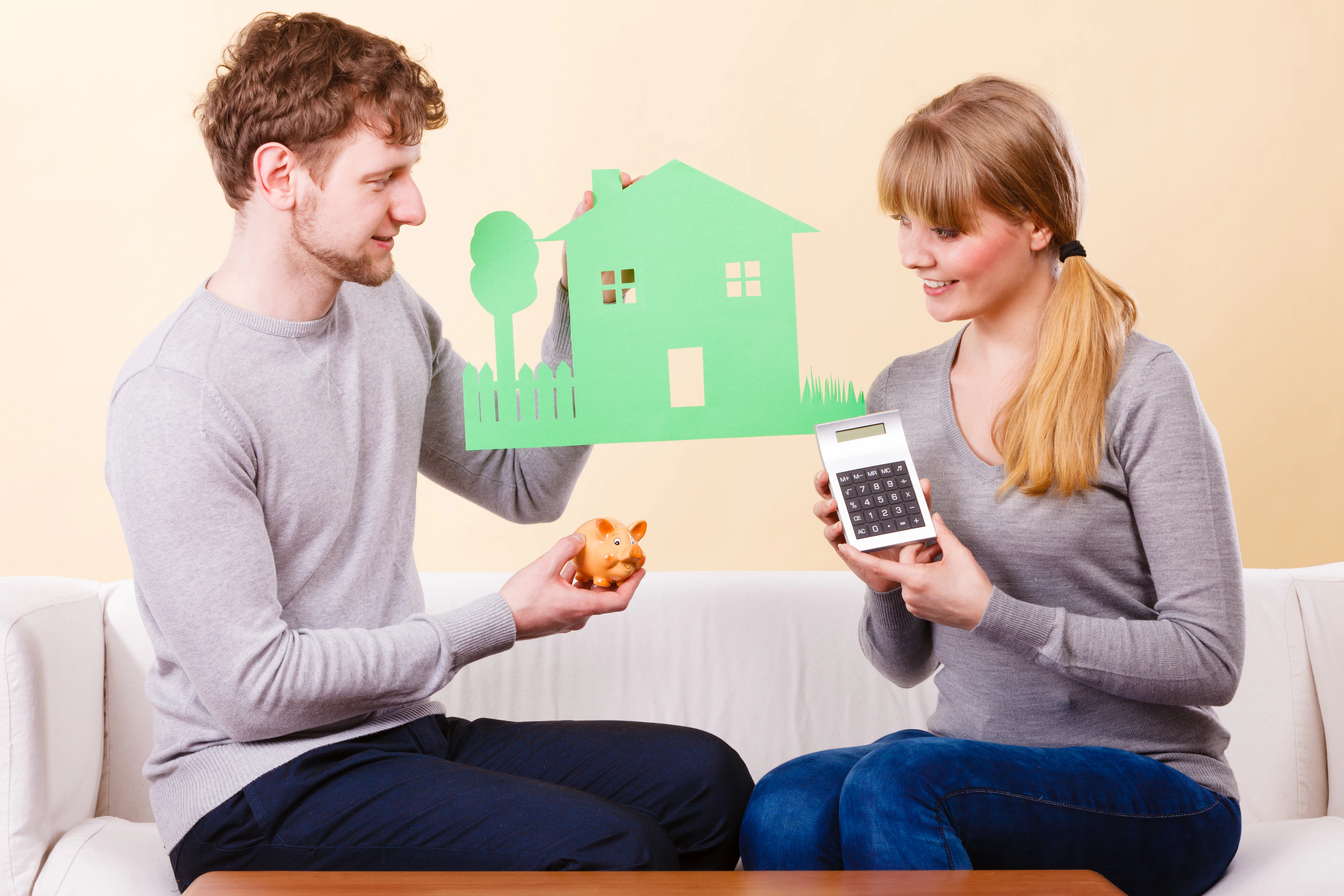 Couple with house and calculator deciding if it's time to buy